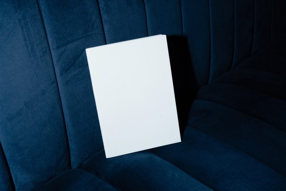 Blank white card angled on deep blue quilted velvet chair with shadow