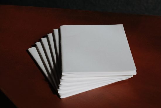 Blank white book mockup with multiple copies on brown leather background, ideal for book cover design presentation.