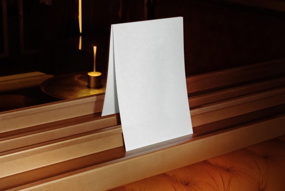 Blank white tent card on wood table with warm gold lighting in dark room