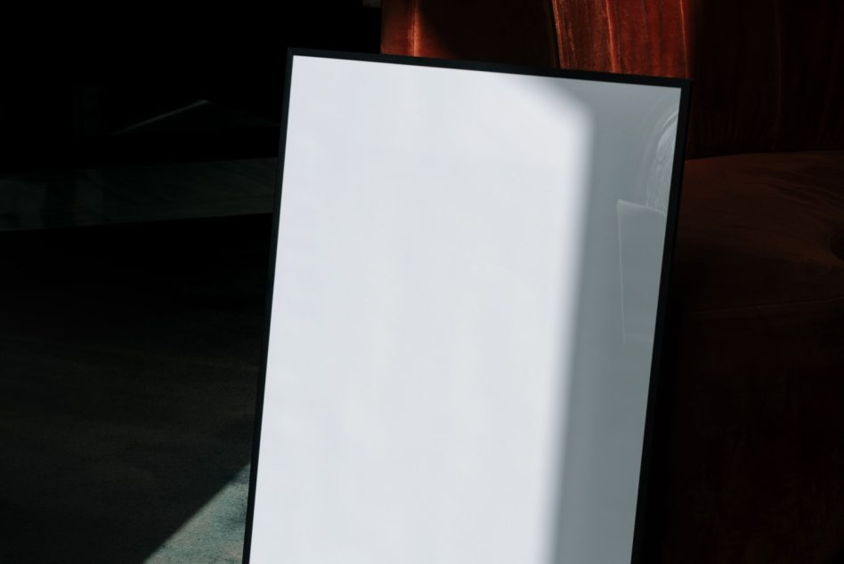Blank poster mockup standing vertical on muted carpet with window light