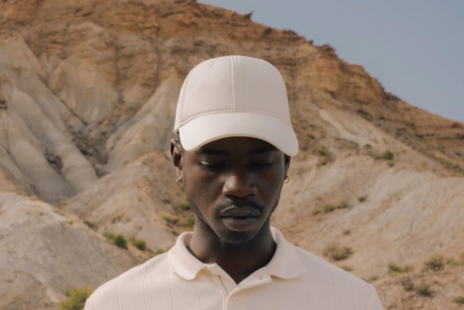 Man in white cap with mountain background for lifestyle mockup, showcasing apparel and accessories in natural light.