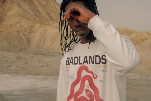 Man wearing white graphic sweatshirt in natural desert setting, ideal for apparel mockup designs, fashion presentations, and template showcases.