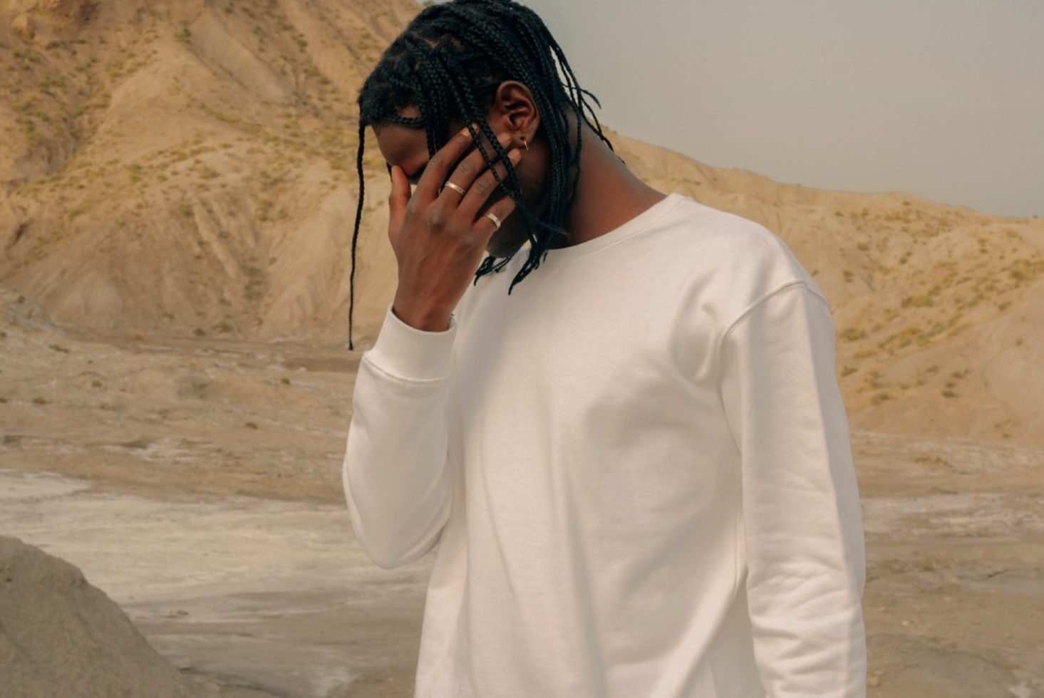 Man in plain white long-sleeve shirt posing in desert setting, ideal for fashion mockups, apparel design, and style presentations.