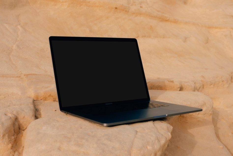 Laptop with blank screen propped on natural stone ledge background