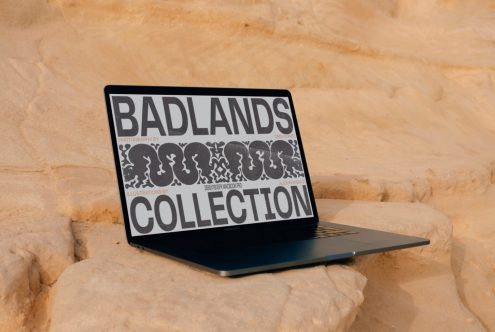 Laptop mockup displaying 'Badlands Collection' outdoor presentation against sandy backdrop, ideal for showcasing design elements.