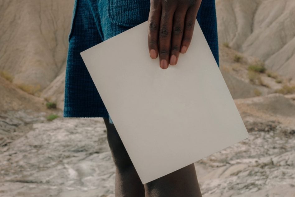 Blank white magazine being held in person's hands on rocky terrain