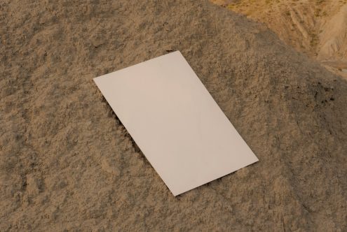 Blank white paper mockup on a textured brown rock surface, ideal for presenting stationery designs and graphics in a natural setting.