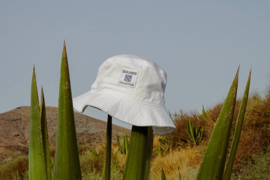 White bucket hat with Badlands Collection label on desert plants