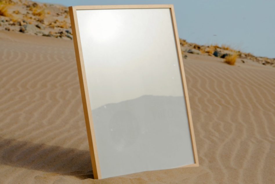 Reflection poster mockup standing angled in desert sands for showcasing designs, suitable for graphics and templates.