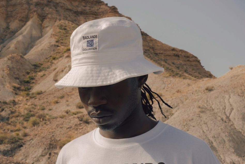 White bucket hat with Badlands Collection label on model in desert setting