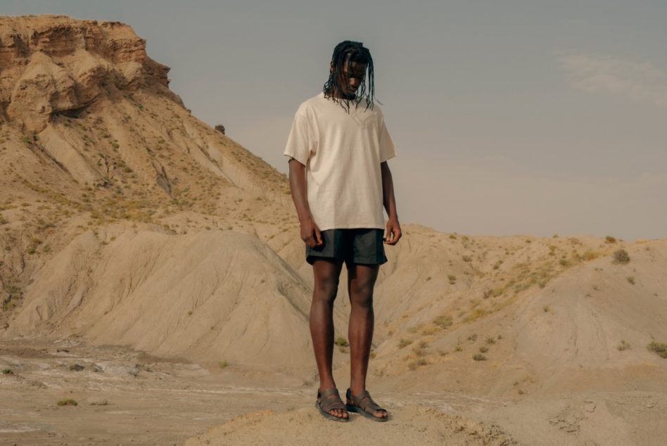 Person standing in desert landscape, wearing casual clothes for fashion mockup, with clear space for design template.