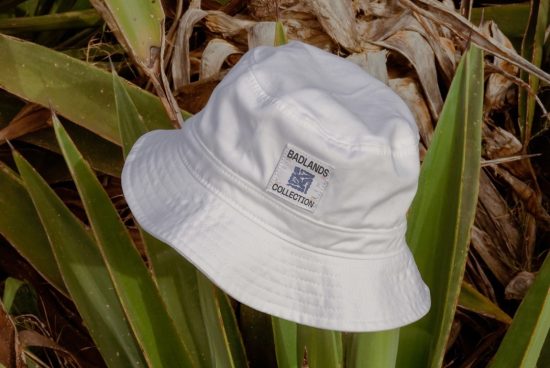 White bucket hat with logo on natural foliage background for apparel mockup design presentations.