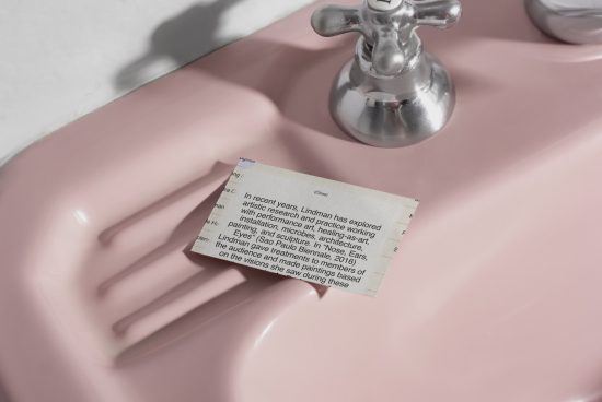 Soft pink soap dish with a piece of newspaper, modern bathroom detail, contemporary graphic design element, minimalism, clean lines.