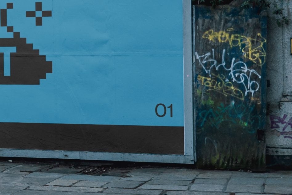 Bright blue wall with pixelated graphic design next to graffiti-covered door