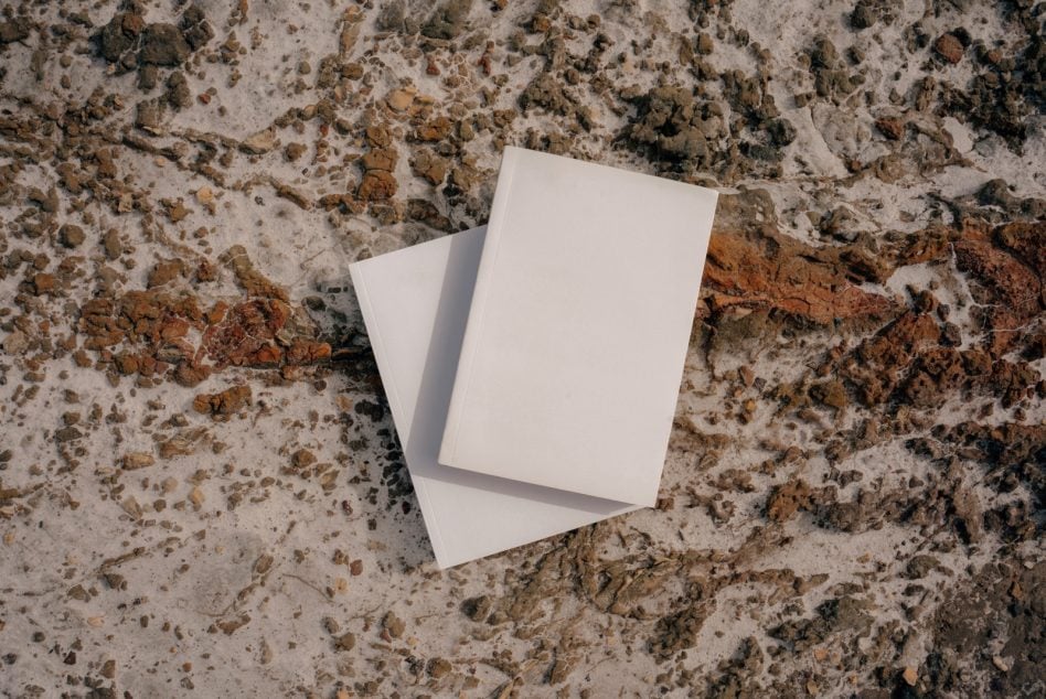 Two blank white cards overlapping on textured concrete with rust stains