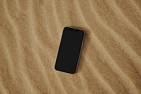 Smartphone with blank black screen on sand texture background