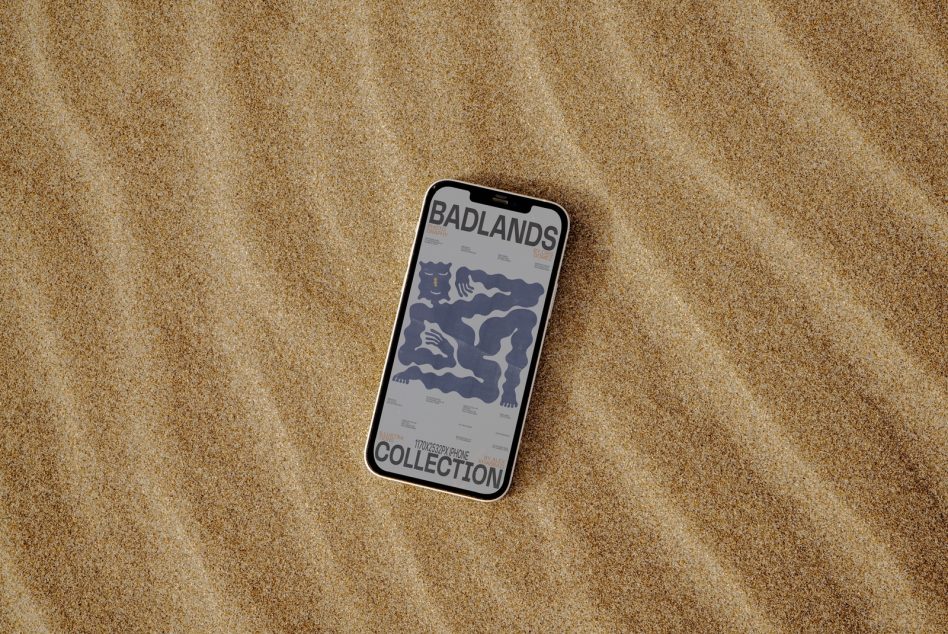 Smartphone mockup on sandy texture displaying graphic design with title Badlands Collection, ideal for showcasing designs to clients.