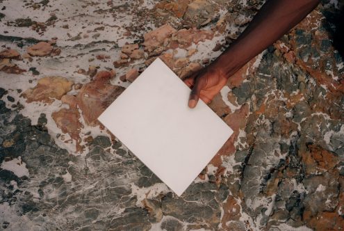 Hand holding blank white card over distressed brick wall texture