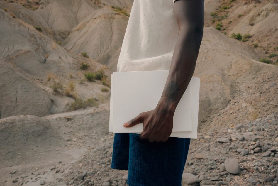 Blank white magazine held in hands outdoors against rocky hills