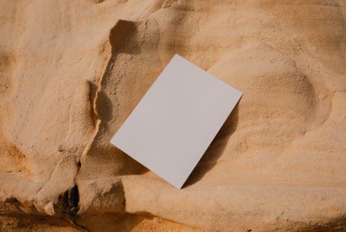 Blank white brochure mockup on textured sand with shadows