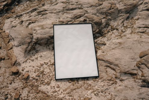 Blank framed poster mockup on textured stone wall surface