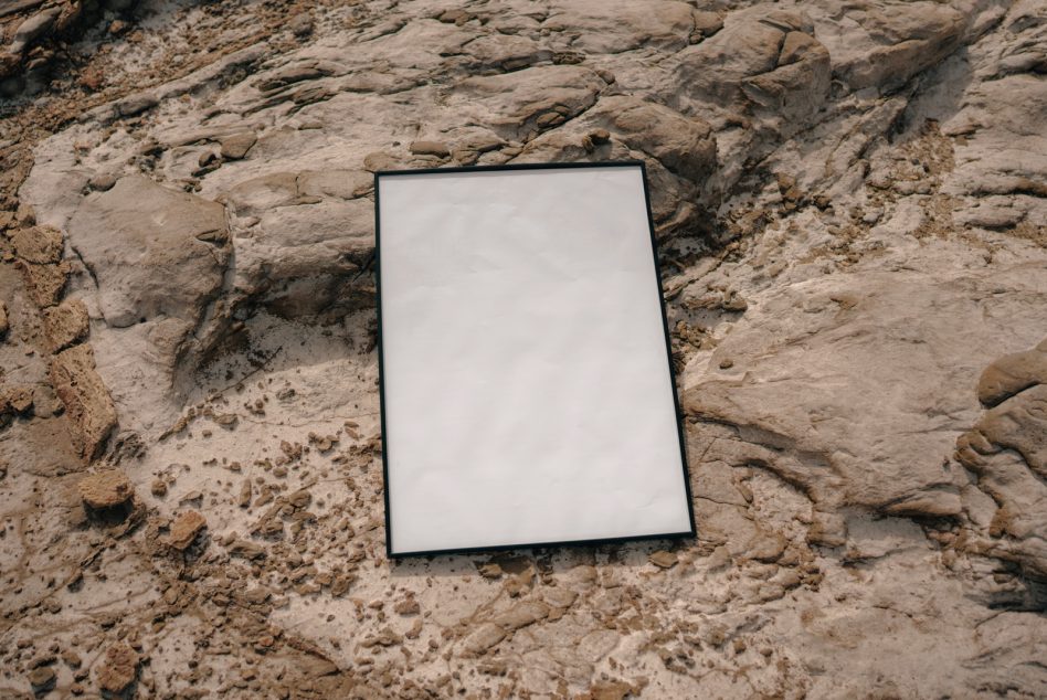 Blank framed poster mockup on textured stone wall surface
