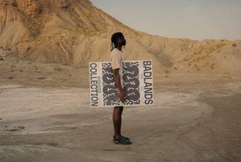 Person holding a graphic poster in a desert landscape, showcasing bold typography and design, ideal inspiration for templates and mockups.