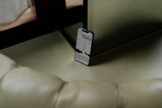 Smartphone on couch displaying elegant script font, ideal for graphic designers seeking stylish typography for branding and web design.
