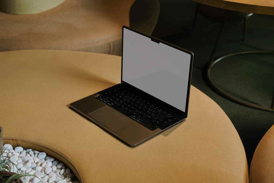 Black laptop on yellow chair showing blank screen in minimal interior space