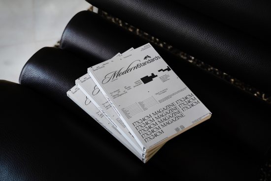 Stack of modern magazines with clean design on a black leather sofa, ideal for mockup graphics and publishing layout templates.