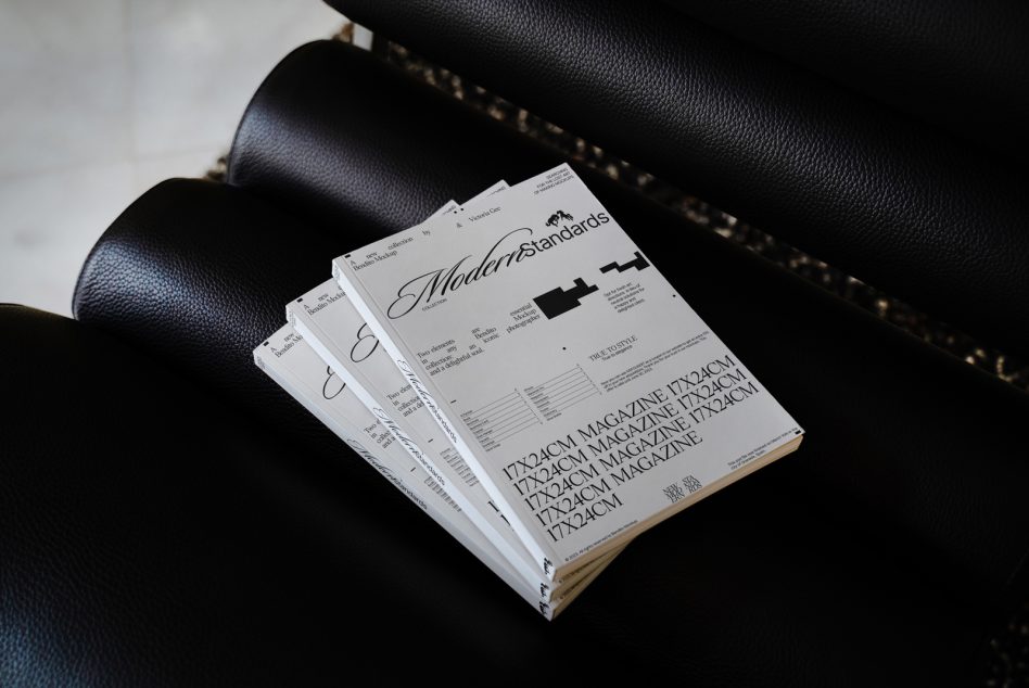 Stack of magazines on black leather sofa with gold stitch details visible