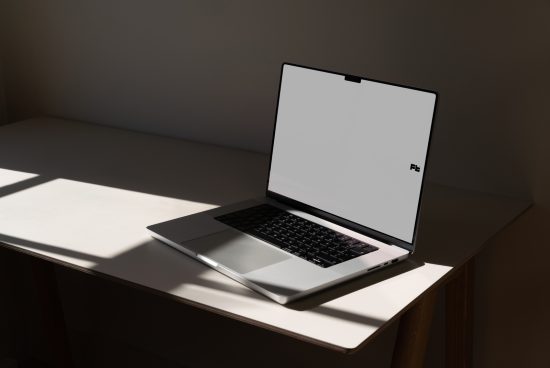Laptop mockup on desk with dramatic lighting, modern design, clean screen, ideal for digital assets, presentations, web templates.