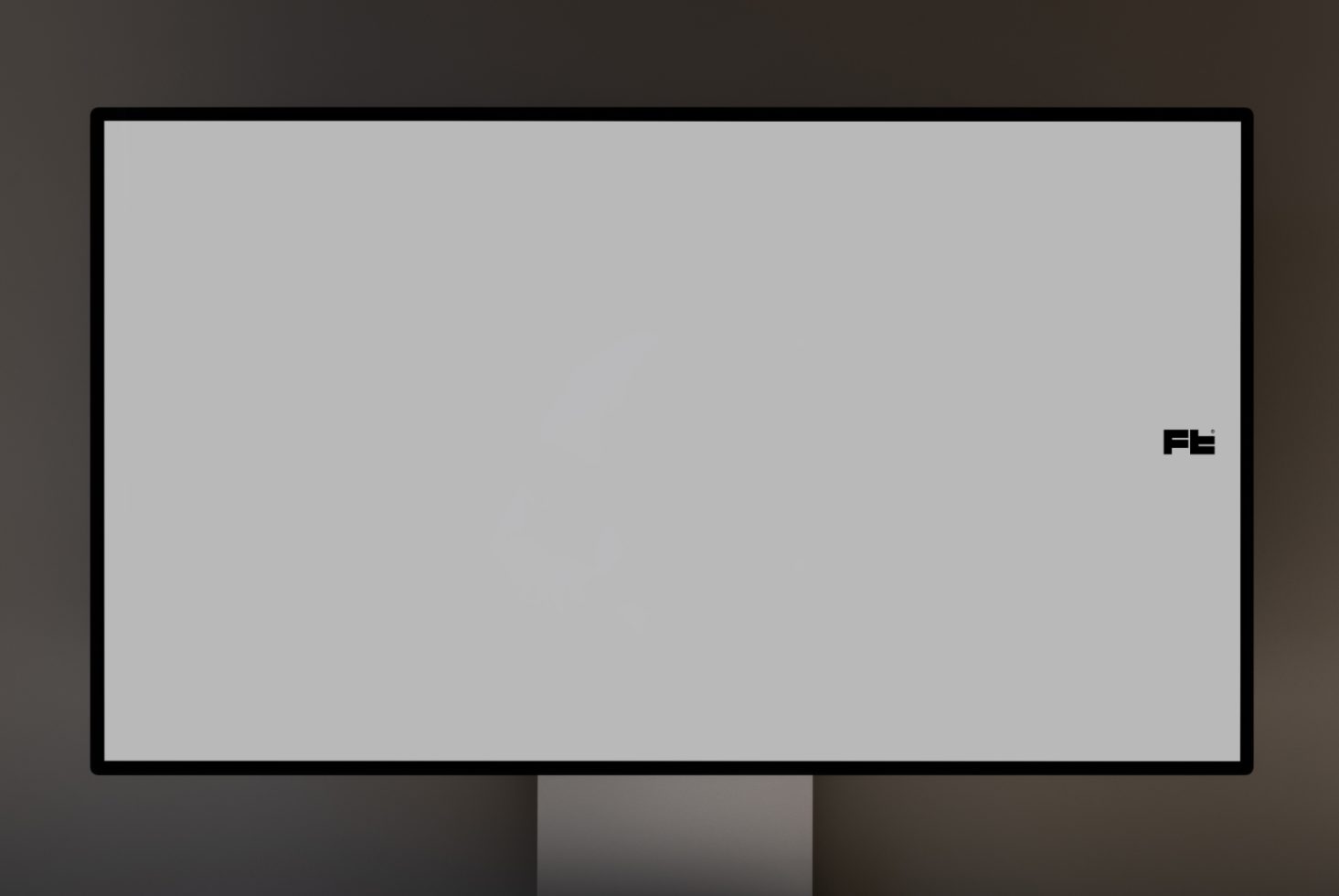 Blank computer monitor mockup with dark bezels on a stand in a dimly lit room, perfect for display designs and templates.