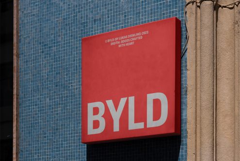 Red billboard mockup with bold BYLD text on a textured blue wall, suitable for graphic design and font display.