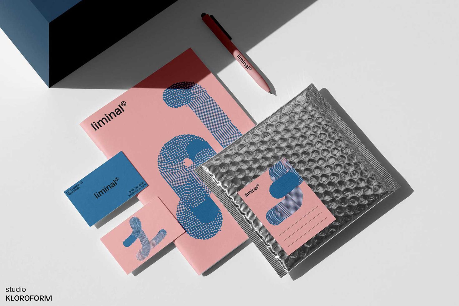 Flat lay of brand identity mockup with notepads, business cards, and pen featuring minimal design with blue halftone graphics.