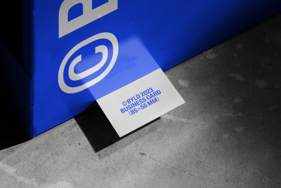 Realistic business card mockup with shadow overlay, concrete background, and a blue corner, showcasing design space for branding.