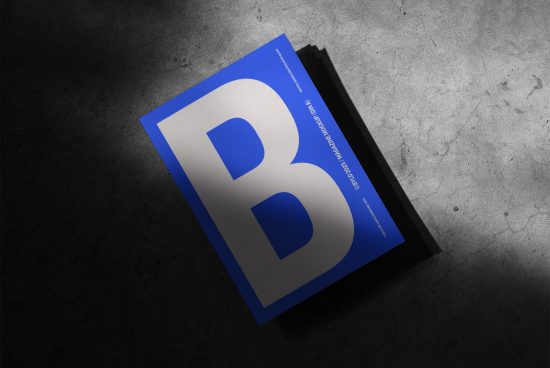 Blue magazine cover mockup with B letter design on textured concrete background, suitable for branding presentations and graphic design.