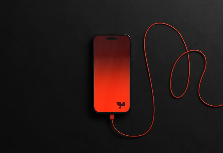 Smartphone mockup with orange screen and cable on a black background, ideal for presenting app designs and mobile interfaces.