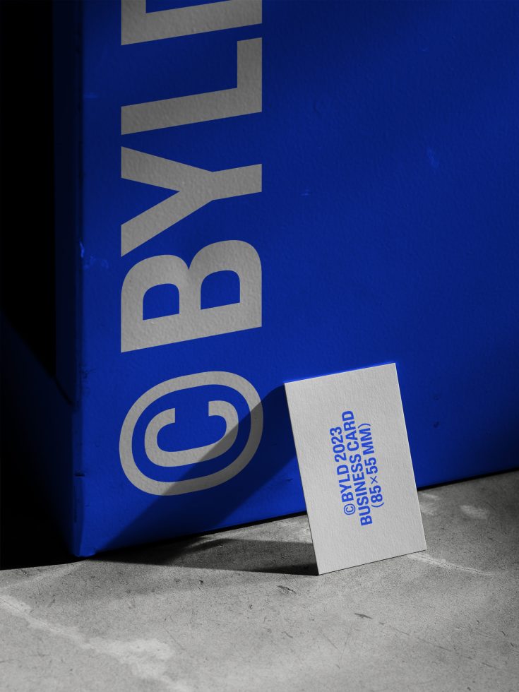 ALT: Business card mockup leaning against blue textured surface with shadow, showcasing design and print quality. Ideal for Templates, Graphics.