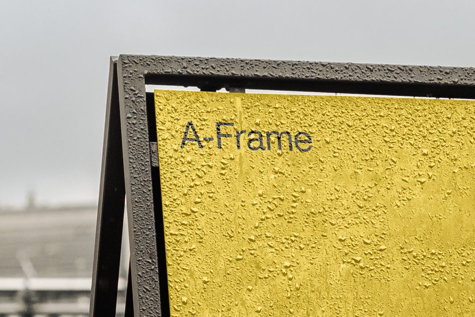 Textured yellow outdoor sign with text on concrete frame closeup