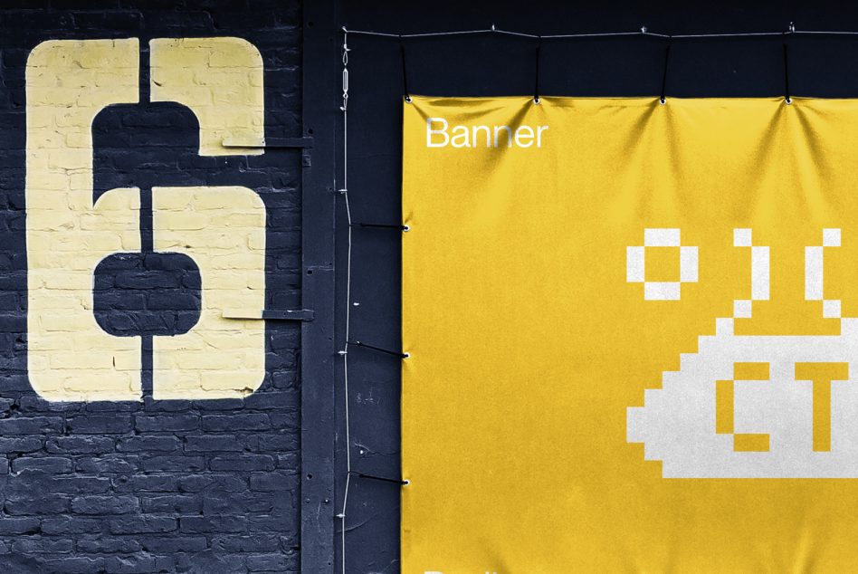 Yellow fabric banner mockup with pixel art UFO graphic next to painted brick sign