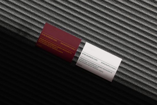 Elegant business card mockup with a white and a maroon card lying on a textured fabric, showcasing design space for branding identity.