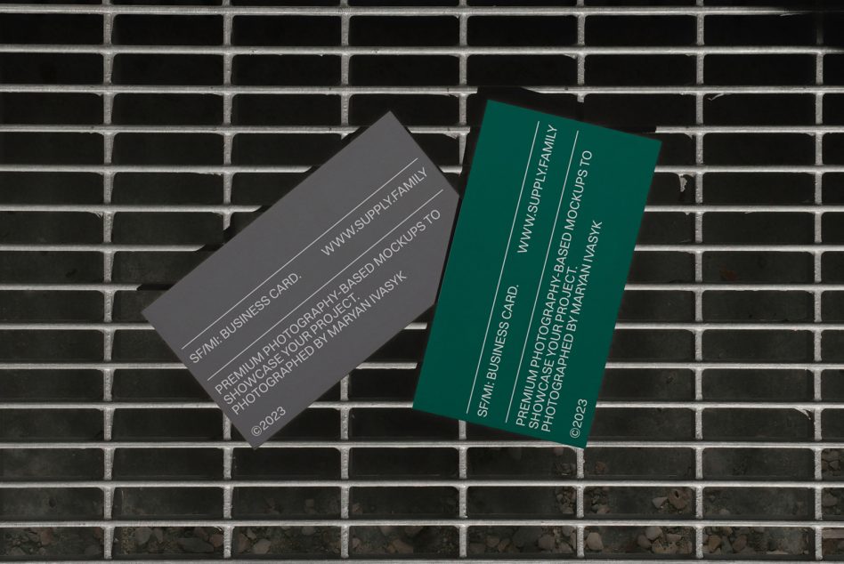 Gray business card tilted left next to green card on brick wall backdrop