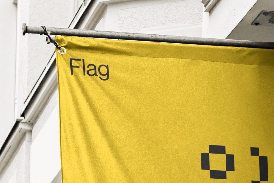 Bright yellow fabric flag hanging from metal rod with text on building exterior