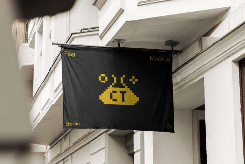 Black hanging flag with yellow text blowing in breeze on building storefront