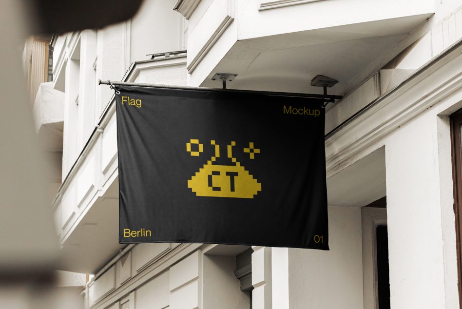 Black hanging flag with yellow text blowing in breeze on building storefront