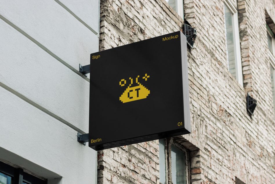 Black corner sign with yellow pixel logo mounted on brick wall