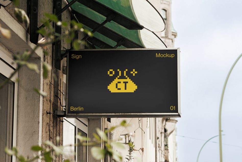 Horizontal black sign with yellow logo mounted on historic building with green awning