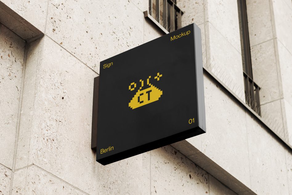 Black wall-mounted sign with yellow pixelated logo on concrete building facade
