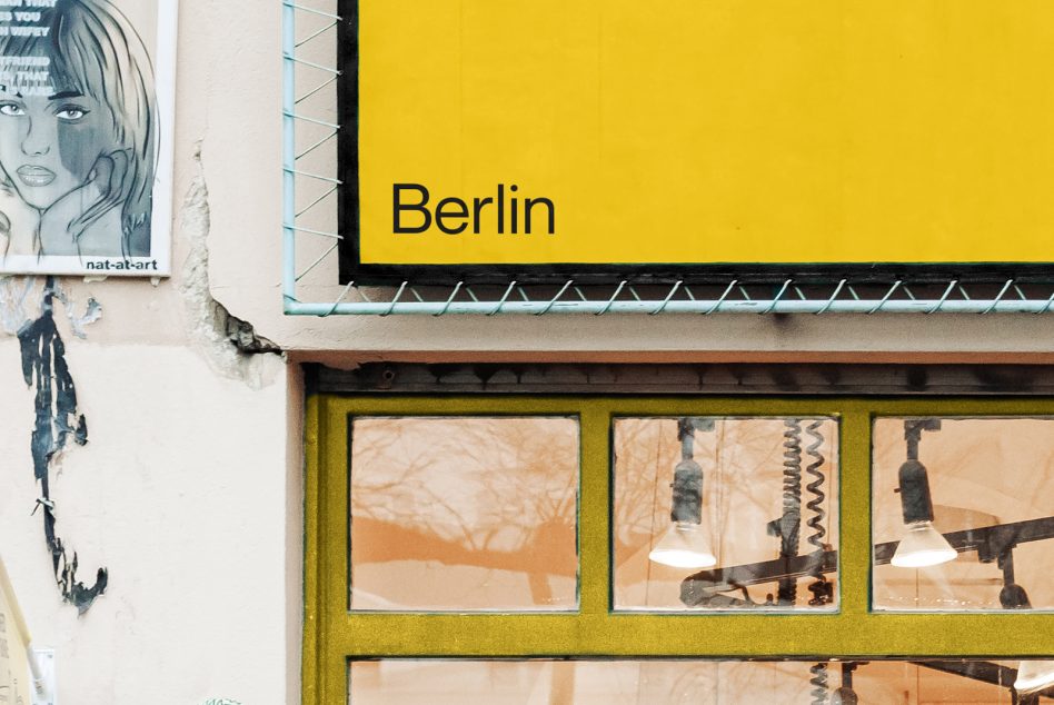 Bright yellow shop sign with Berlin text over olive-framed windows